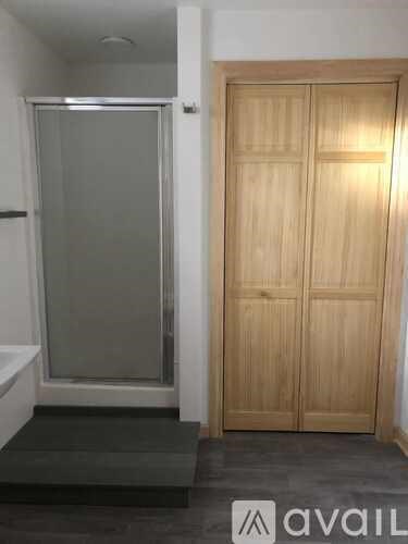 A bathroom with a glass shower door and a wooden door.