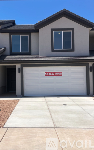 A house with a garage door that has a "Sold" sign on it.