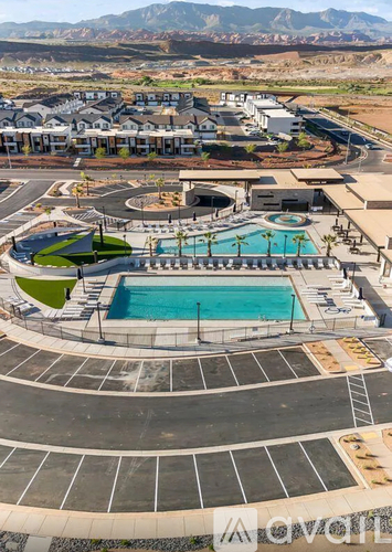 A large outdoor swimming pool surrounded by a grassy area and a mountain range in the background.