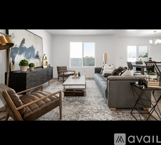 A living room with a grey couch, a brown leather chair, a wooden coffee table, and a large abstract painting on the wall.