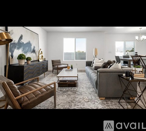 A living room with a grey couch, a brown leather chair, a wooden coffee table, and a large abstract painting on the wall.