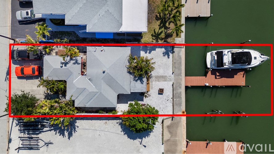 A dock extends into a greenish body of water with a building in the background.