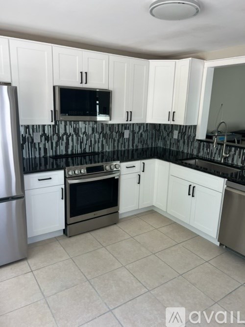 A kitchen with white cabinets and a black and white tiled backsplash.