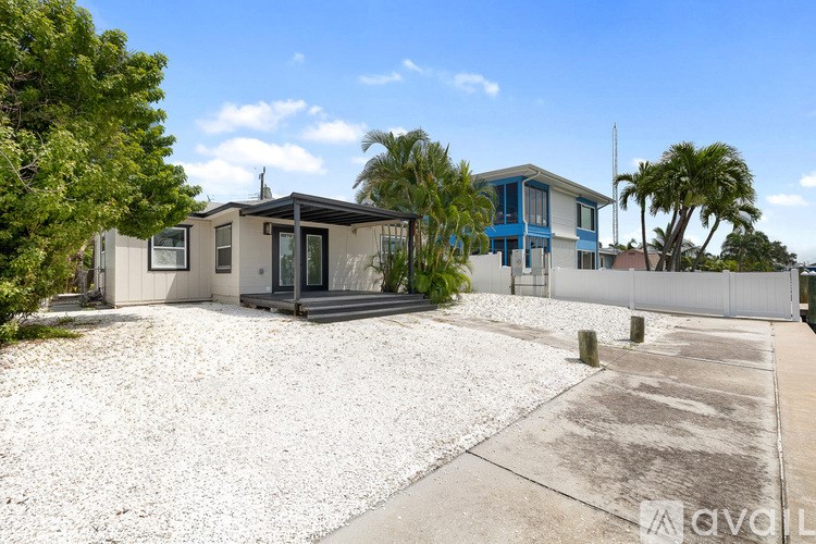 A modern house with a gravel driveway and a white fence.