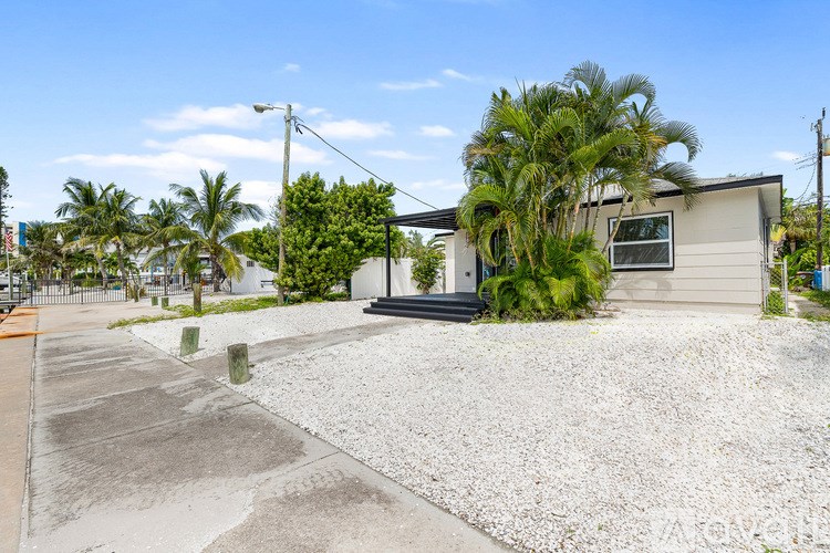 A house with a driveway and a palm tree in front.