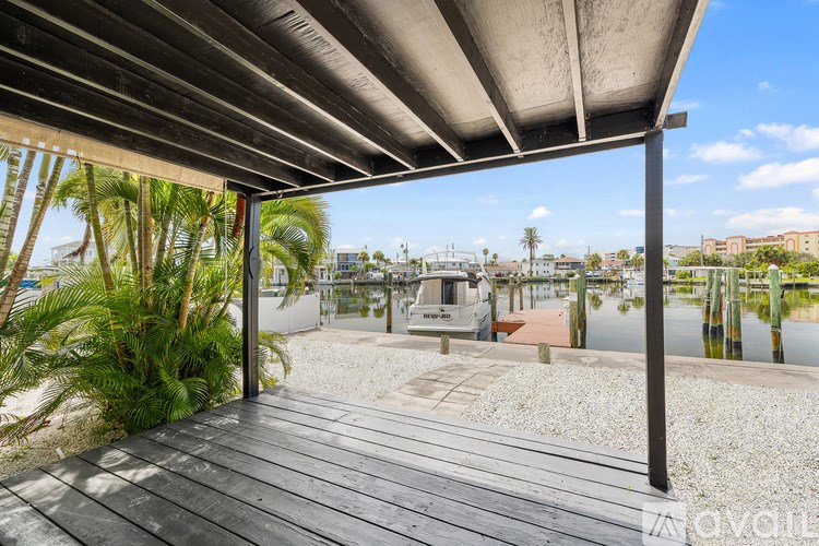 A wooden deck with a metal roof overlooks a marina with boats.