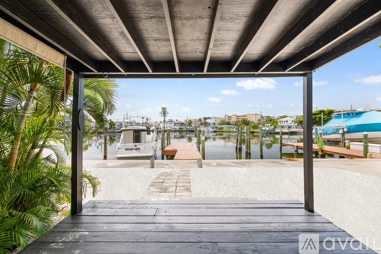 A wooden deck with a white railing overlooks a body of water with boats docked.