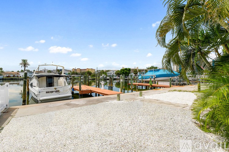 A boat is docked at a marina with a palm tree in the foreground.