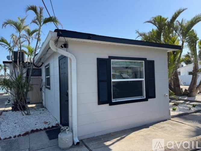 A small white house with a black roof and a window with black shutters.