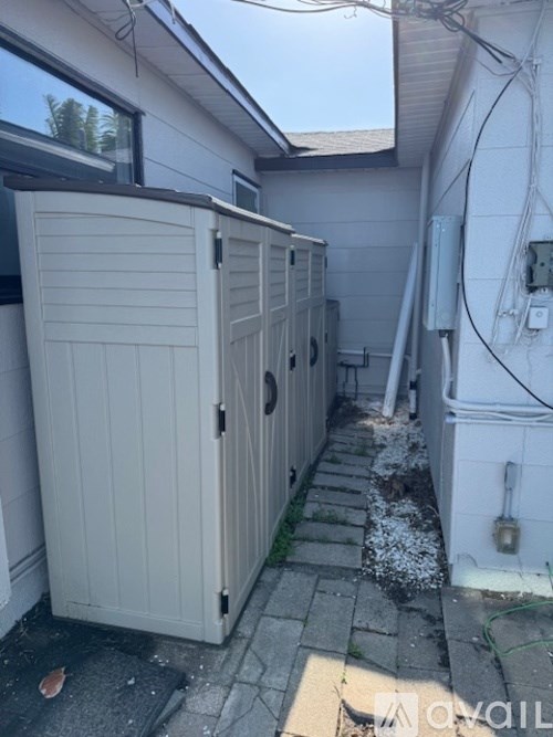A row of four beige outdoor heaters are lined up on a concrete patio.