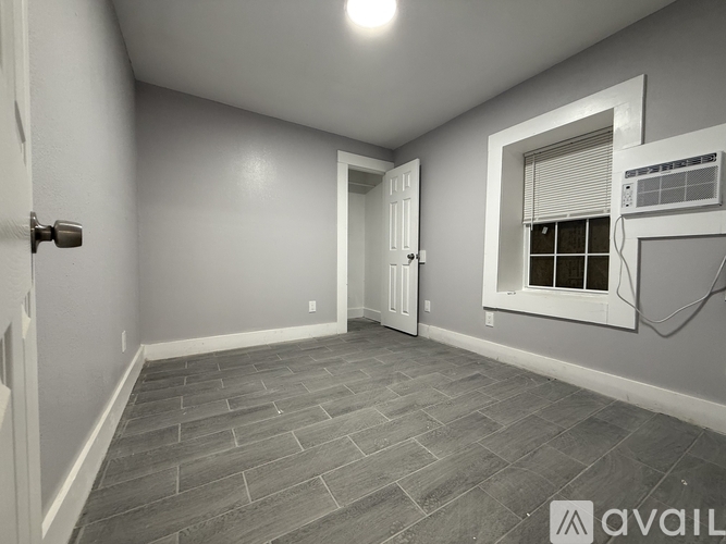 A room with a door, window, and a wall-mounted air conditioner unit.