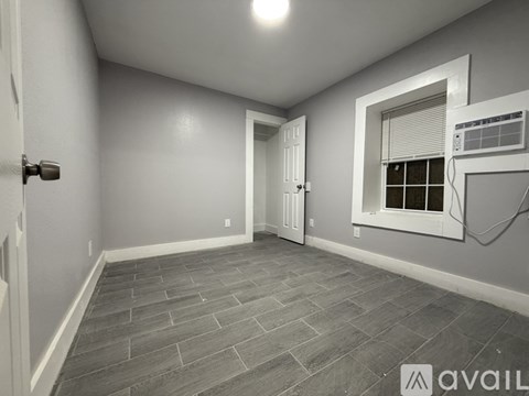 A room with a door, window, and a wall-mounted air conditioner unit.