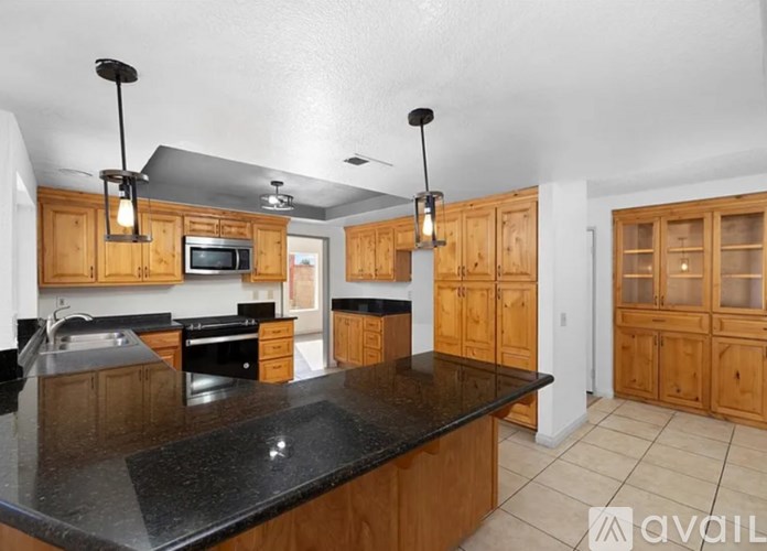 A kitchen with wooden cabinets and black countertops.