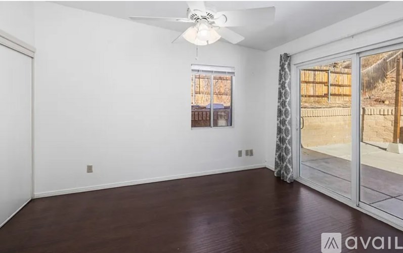 A room with a ceiling fan and sliding glass doors.