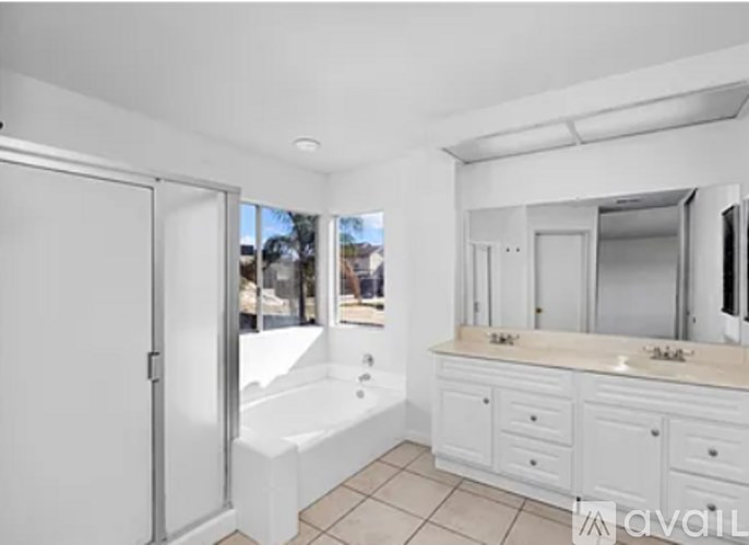 A white bathroom with a tub, sink, and mirror.