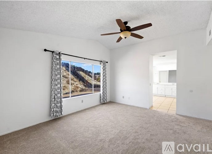 A room with a ceiling fan and a window with a view of a mountain.