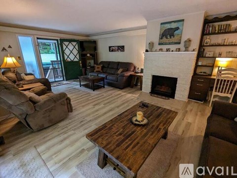 A living room with a fireplace and a painting of a bear above it.