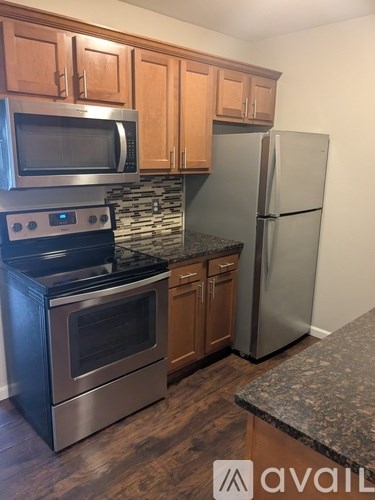 A kitchen with a stove top oven, microwave, refrigerator, and cabinets.