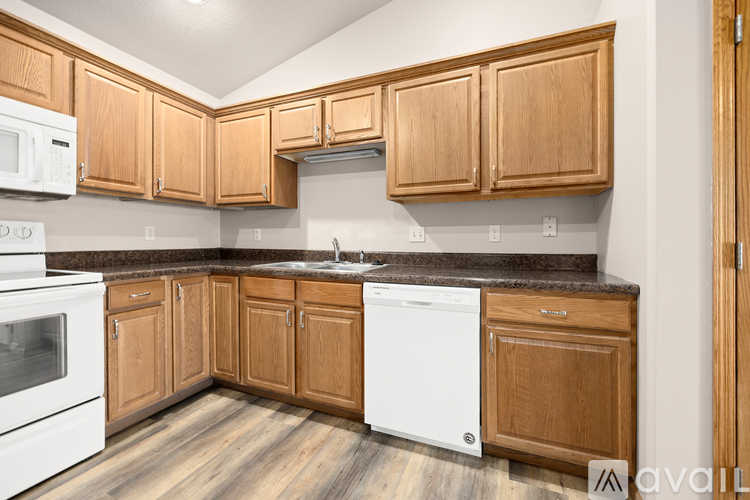 A kitchen with wooden cabinets and a white dishwasher.