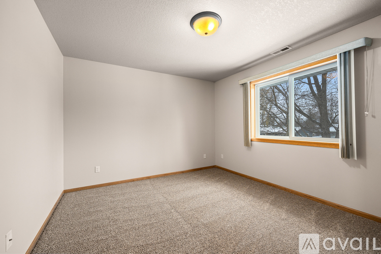 A room with a carpeted floor and a window showing trees outside.