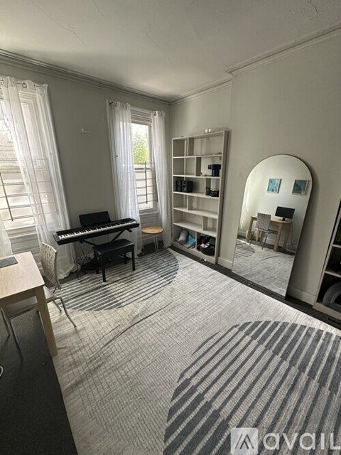 A room with a piano, a chair, and a mirror.