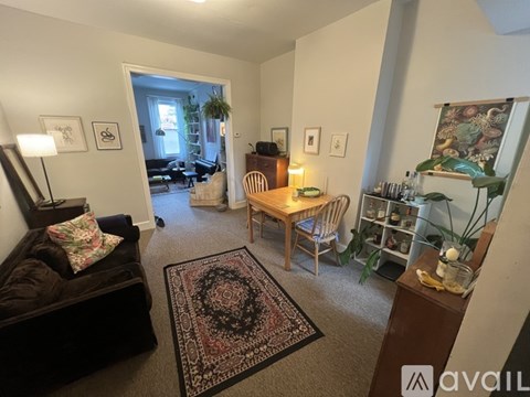 A living room with a couch, rug, and a table with a lamp on it.