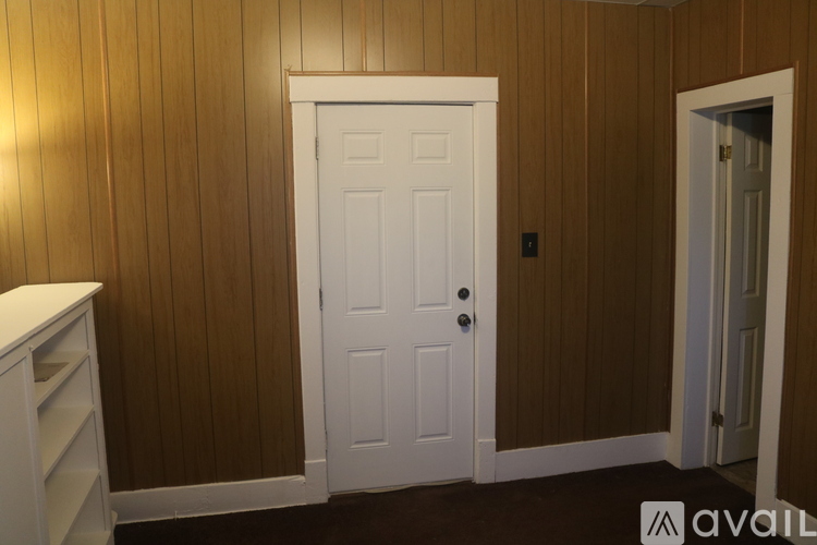 A white door is in the middle of a room with brown walls.