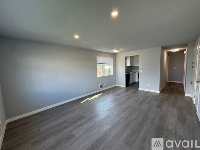 A spacious room with wooden flooring and a window.