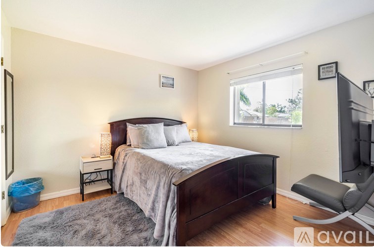 A bedroom with a bed, nightstand, chair, and window.