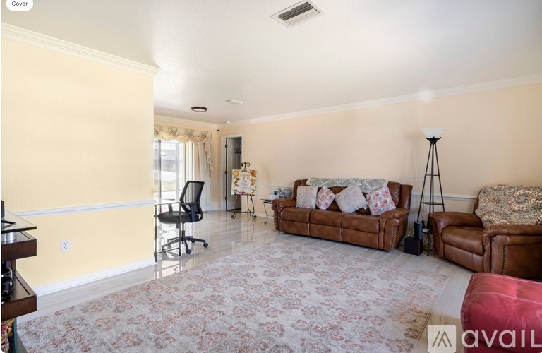 A living room with a carpet, a brown couch, a chair, a floor lamp, and a small table with a plant on it.