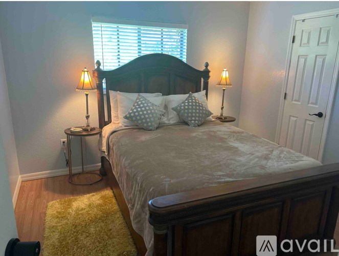A bedroom with a bed, two lamps, and a yellow rug.