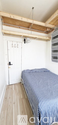 A room with a bed, a window with red curtains, and posters on the wall.