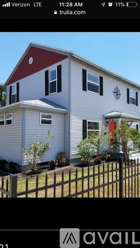 A house with a red roof and a fence in front.