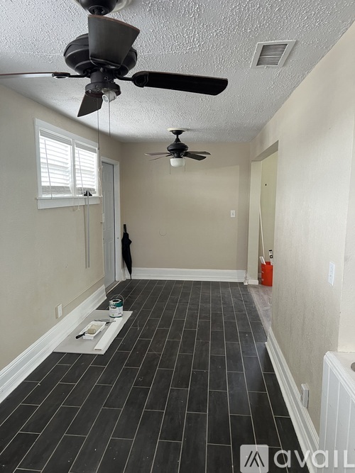 A room with a ceiling fan and tile flooring.