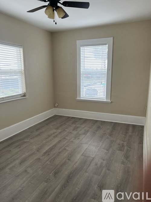 A room with a ceiling fan and two windows with blinds.