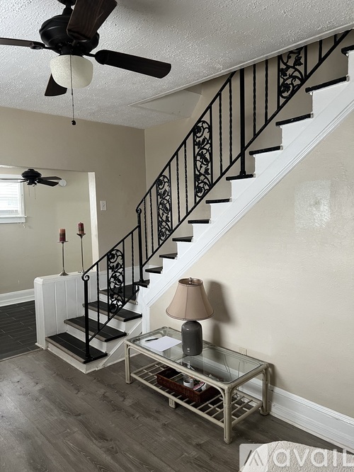 A living room with a staircase and a fan.