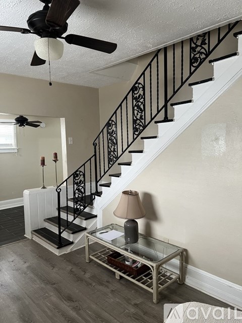 A living room with a staircase and a fan.