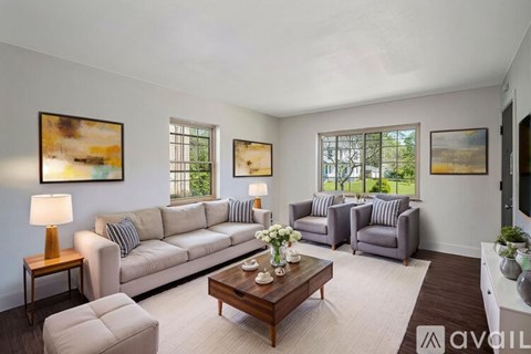 A living room with a grey couch, a wooden table, and a painting on the wall.