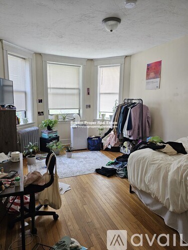 A room with a bed, desk, and clothing rack.