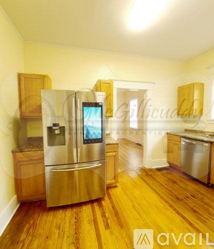 A kitchen with wooden floors and a stainless steel refrigerator.