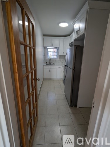 A kitchen with white cabinets and a refrigerator.