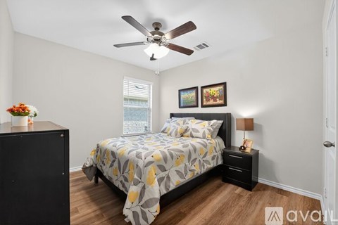 A bedroom with a bed, nightstand, and a ceiling fan.