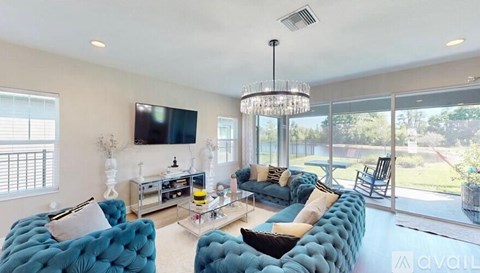 A living room with blue chairs and a flat screen TV mounted on the wall.