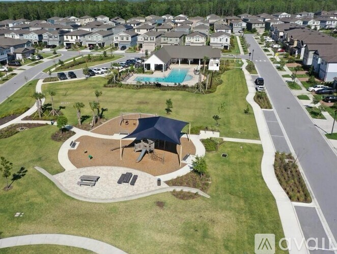 A bird's eye view of a neighborhood with a large swimming pool and a pavilion.