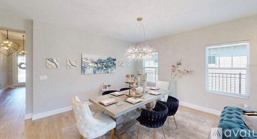 A dining room with a table set for four and a chandelier hanging from the ceiling.