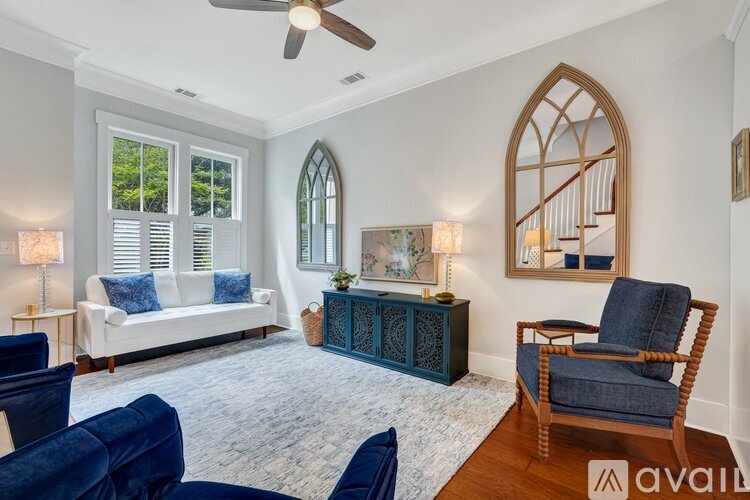 A living room with a white couch, a blue chair, and a wooden floor.