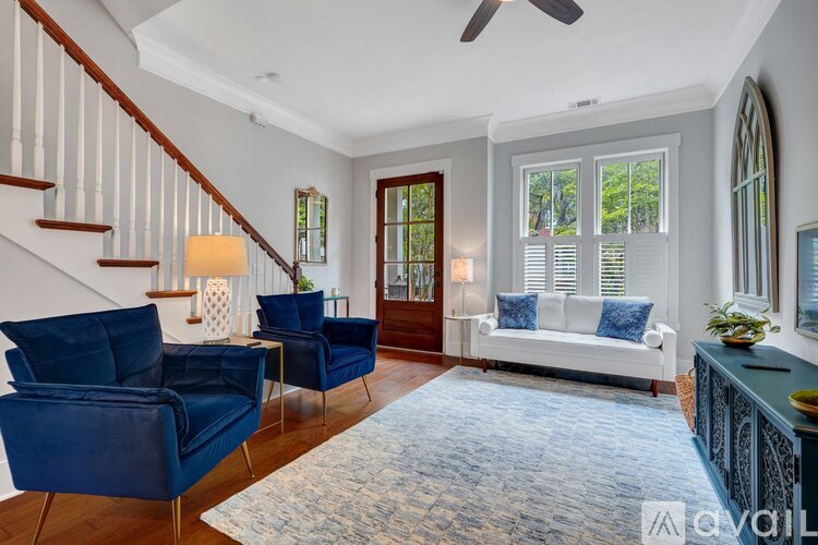 A living room with a staircase and blue chairs.