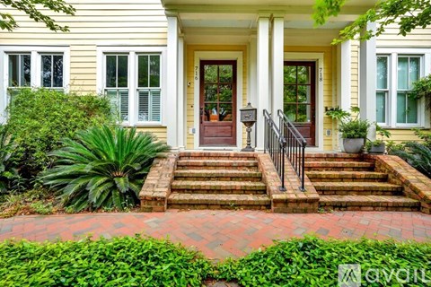 A yellow house with a red door and steps leading up to it.