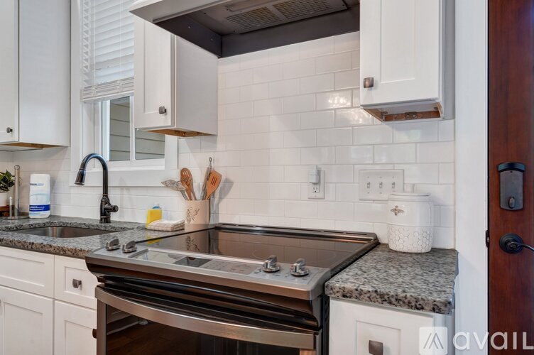 A modern kitchen with white cabinets and a granite countertop.