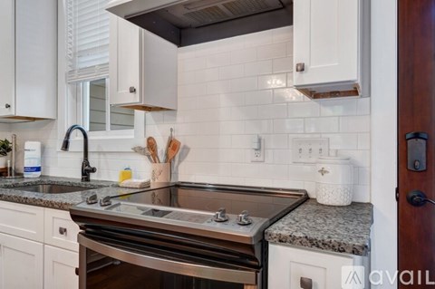 A modern kitchen with white cabinets and a granite countertop.